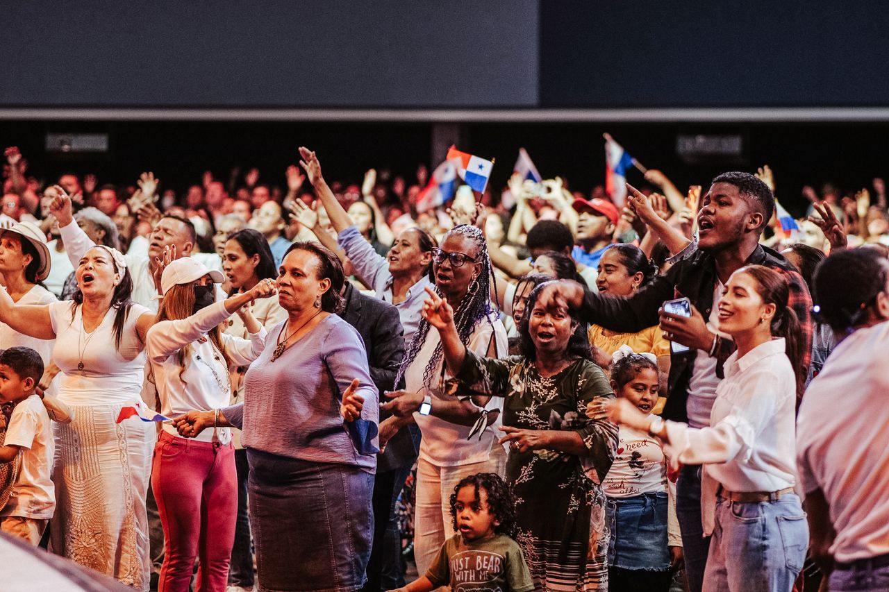 A diverse group celebrating together with flags, displaying unity and joy in an indoor event.